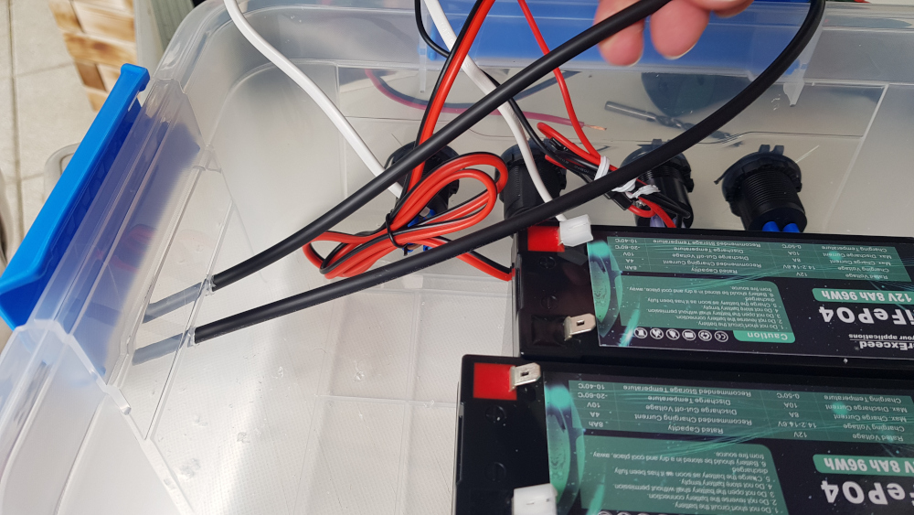 Durch zwei weitere Löcher werden die Solarkabel in die Kiste gezogen